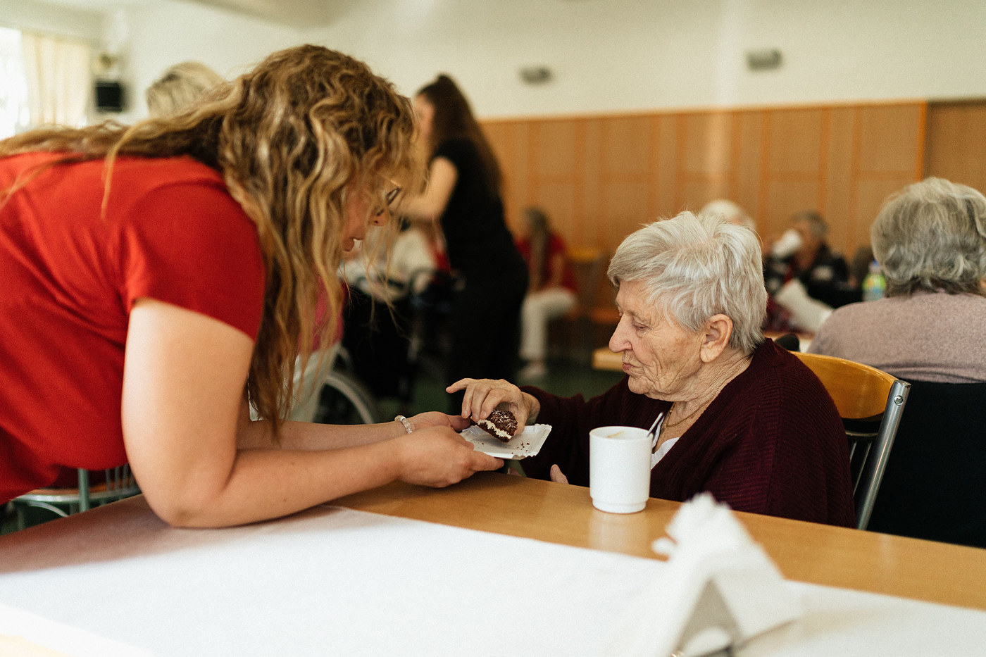 Care worker supporting a resident during a communal meal in a care home