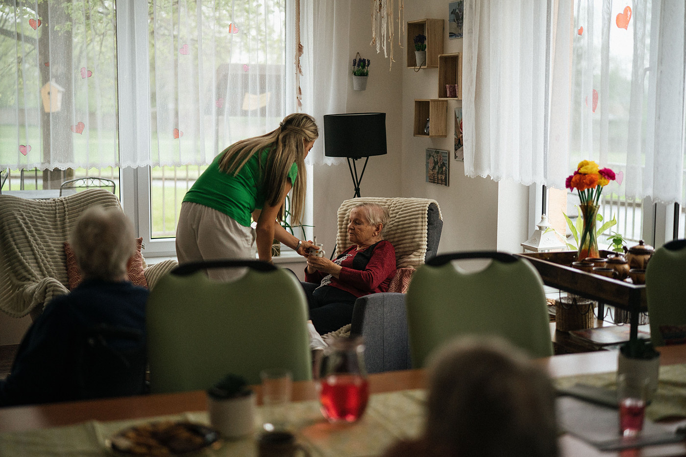 Care worker attending to a resident in a warm, home-like communal care setting