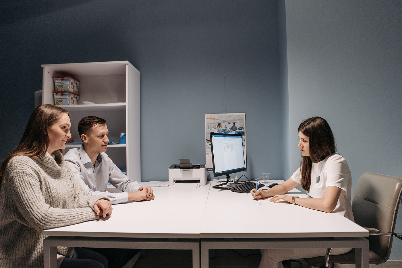 Clinical pharmacist consulting with two patients at a desk