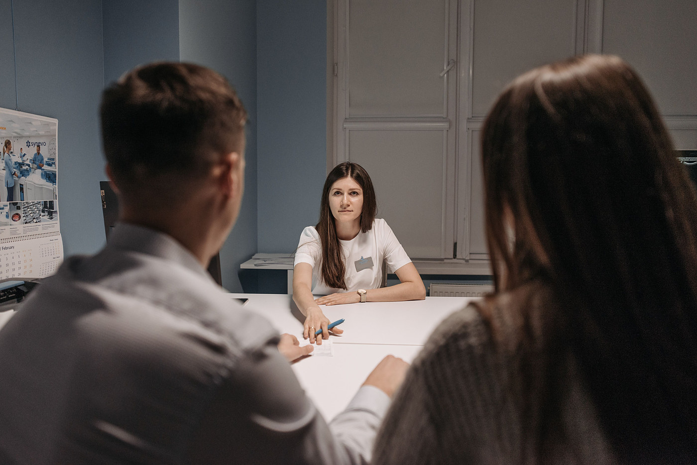 Clinical pharmacist consulting with two patients at a desk